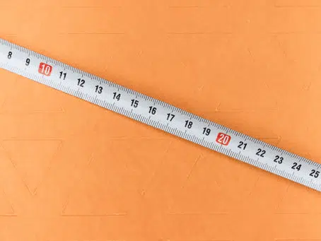 Metal ruler with measurement markings placed on an orange surface.
